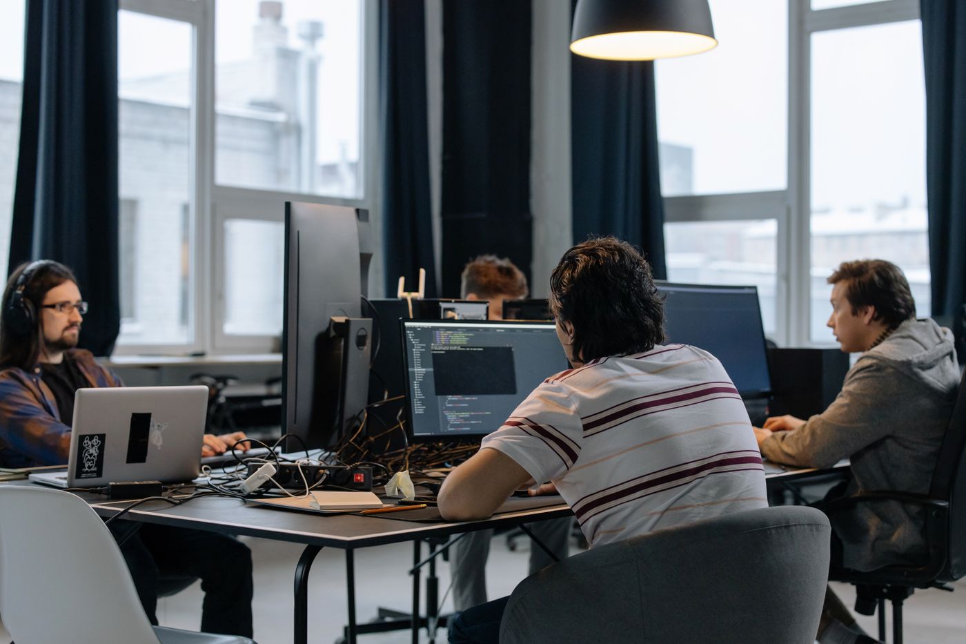 Ontwikkelteam werkt achter meerdere schermen met code in een moderne kantooromgeving