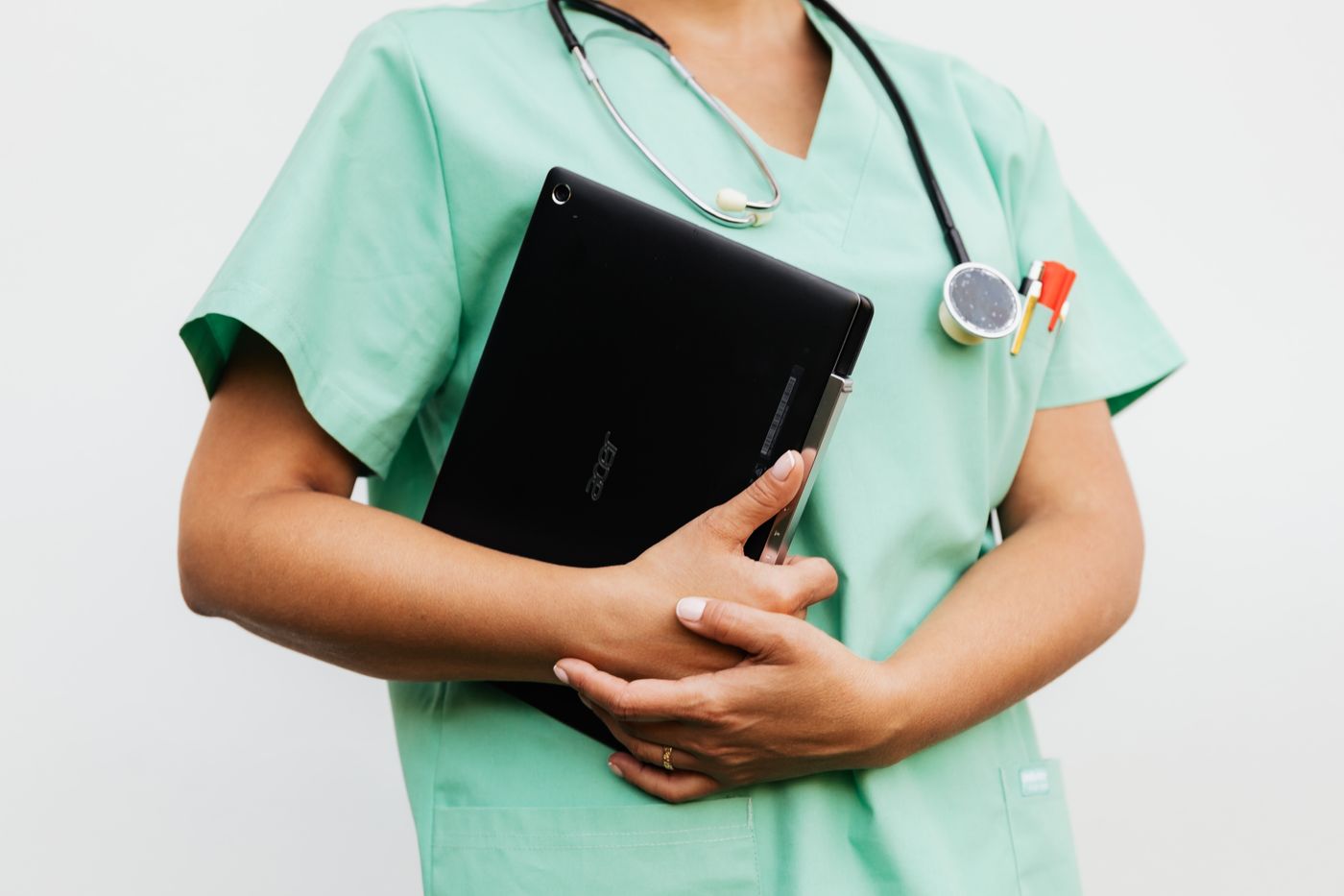 Zorgmedewerker in operatiekleding met een tablet onder de arm en een stethoscoop om de nek